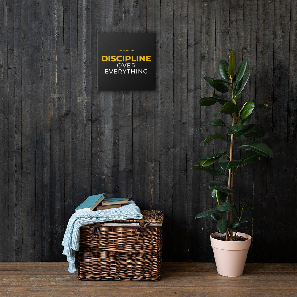 Discipline Over Everything Canvas hanging on a dark wood wall