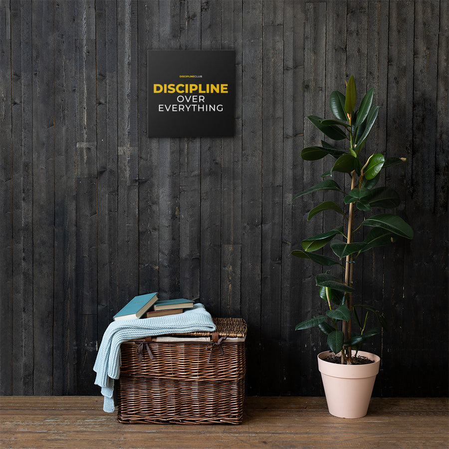 Discipline Over Everything Canvas hanging on a dark wood wall